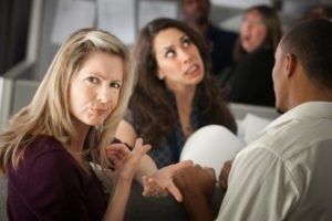 AnnoyedWomanWithCoworkersInOfficeCubicleShutterstock